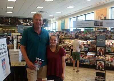 A man and a young girl display their copy of Beautiful Evil Winter at Kelly K. Lavender's Barnes & Noble Booksigning